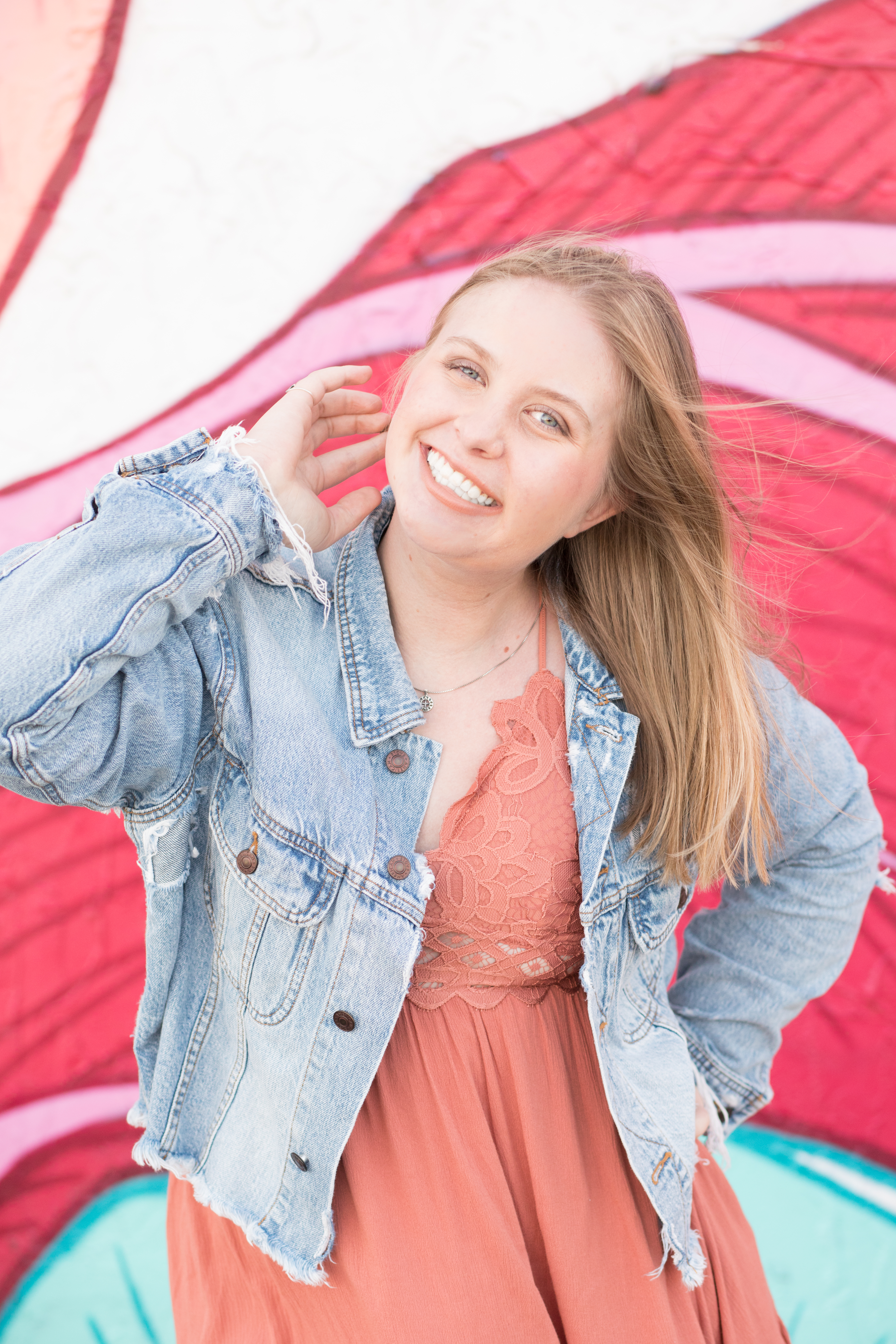 senior portrait in front of bright pink mural in Jacksonville, FL